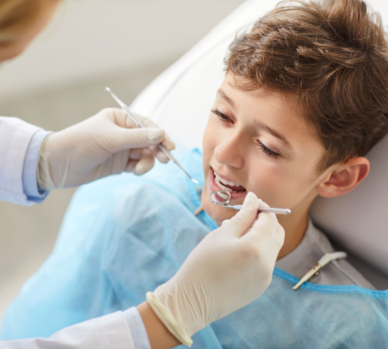 Female dentist in clinic treating childs teeth, close-up. Dental checkup of boy, caries treatment. Concept child dental checkup, dental hygiene, health care and medicine, dental hygiene